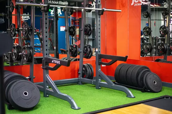 Multi-Purpose Squat Rack with Barbell and several Weight Plates in front of a Mirror in a Gym