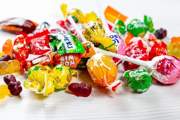 Multicolored lollipops and jelly candies on white wooden background
