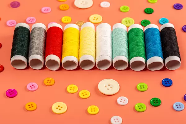 Multicolored threads and buttons on an orange background