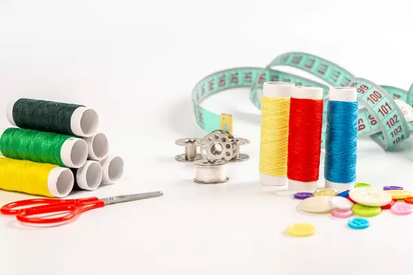 Multicolored threads, buttons, scissors and measuring tape on white