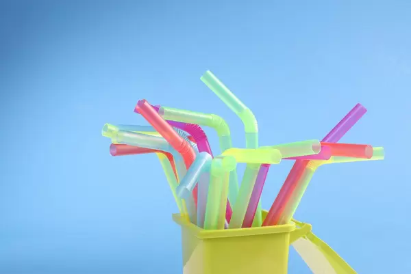 Multicoloured plastic drinking straws on blue background