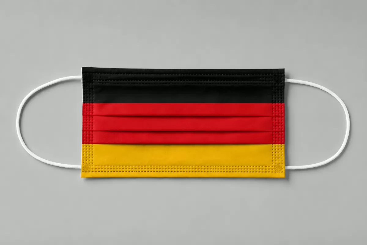 Mundschutzmaske im deutschen Flaggen-Design auf grauem Hintergrund