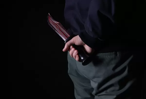 Murderer holding knife in blood