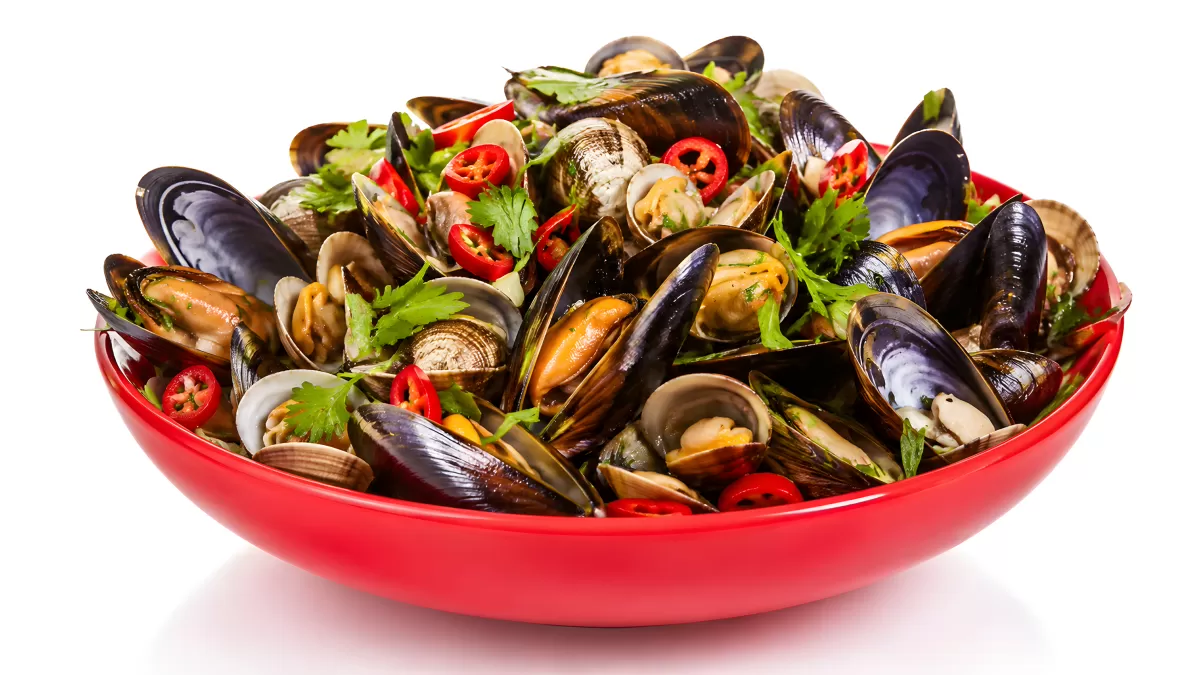 Muscheln und Venusmuscheln in roter Schüssel mit Chili