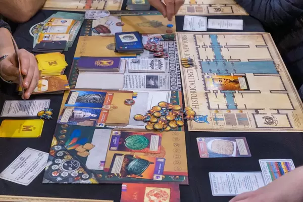 Museum Brettspiel ausgebreitet auf einem Tisch und von Messebesuchern gespielt