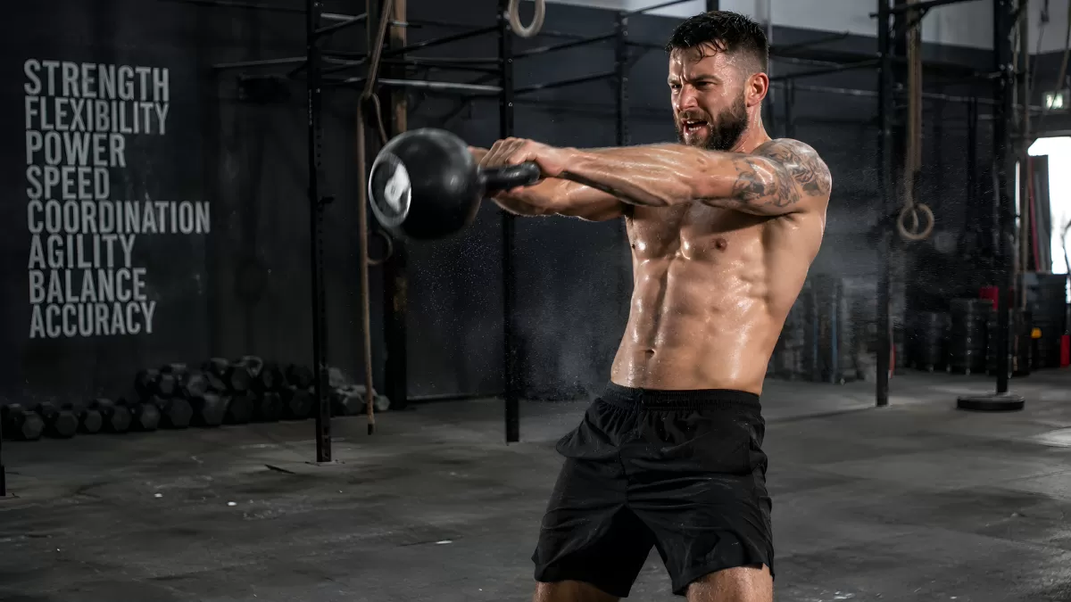 Muskulöser Mann beim Kettlebell-Schwingen im CrossFit-Studio