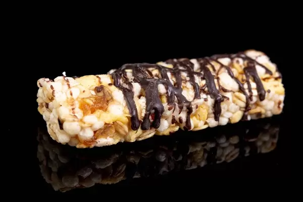 Müsliriegel mit Banane und Überzug aus dunkler Schokolade liefert Energie, isoliert vor schwarz