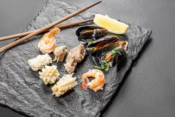Mussels, shrimp, squid and fish on a black stone background (Flip 2019)