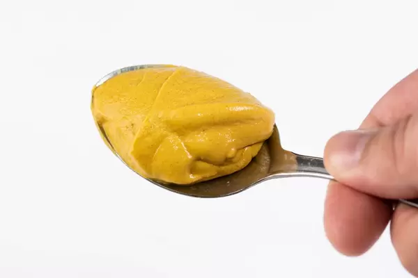 Mustard on the spoon above white background (Flip 2019)