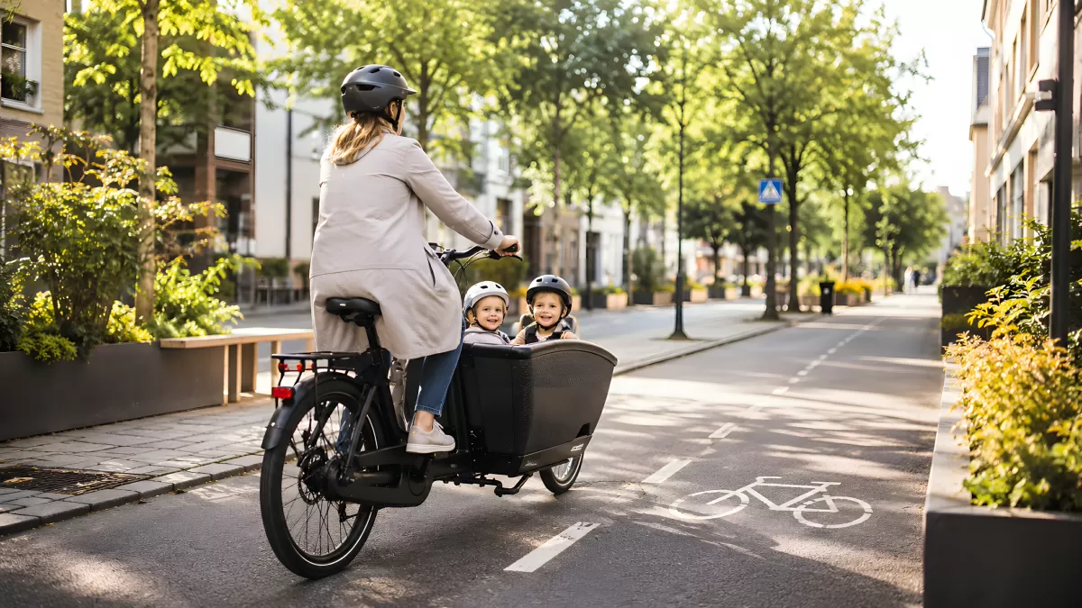 Mutter fährt mit zwei Kindern im Lastenrad durch die Stadt