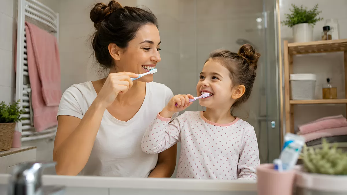 Mutter und Tochter putzen gemeinsam Zähne im Bad
