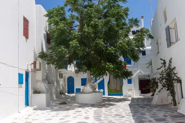 Mykonos: kleiner Platz mit Baum in der Mitte und weißen Häusern mit blauen Türen und Fenstern