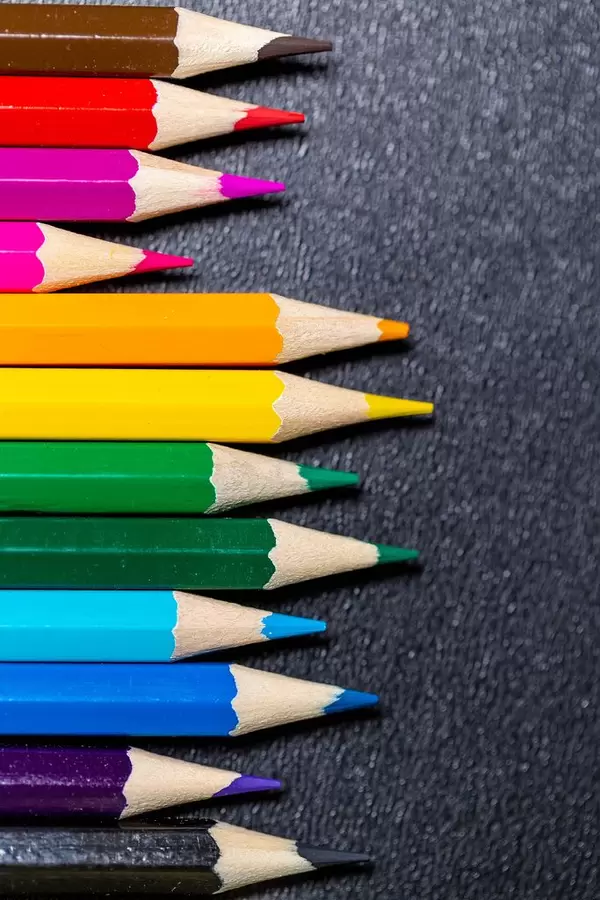 Nach Farben sortierte Buntstifte auf schwarzem Untergrund