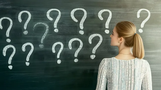 Nachdenkliche Frau vor Tafel mit Fragezeichen