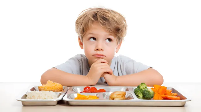 Nachdenklicher Junge betrachtet gesunde Mahlzeit