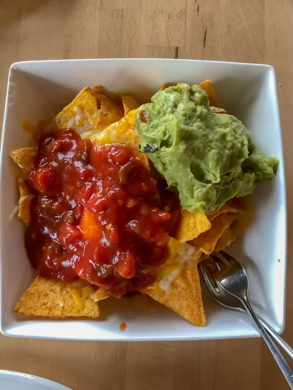 Nacho-Chips mit Guacamole aus Avocado und Dip auf Tomatenbasis auf Holztisch