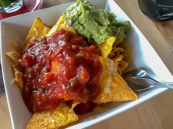 Nachos mit Guacamole und Tomatensalsa in weißer Schüssel