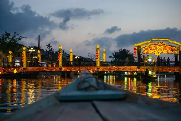 Nacht Foto von der Brücke der Lichter mit Touristen auf Booten mit beleuchteten Laternen und Reflektionen im Thu Bon Fluss in Hoi An, Vietnam
