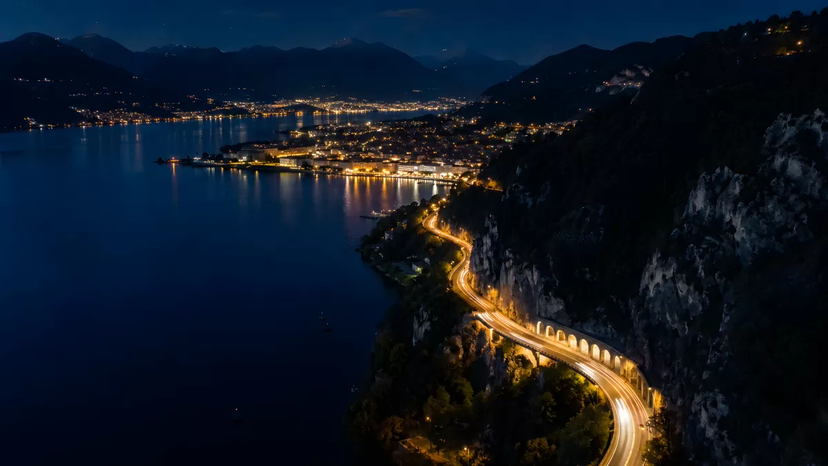 Nächtliche Küstenstraße am Bergsee mit Lichtspuren