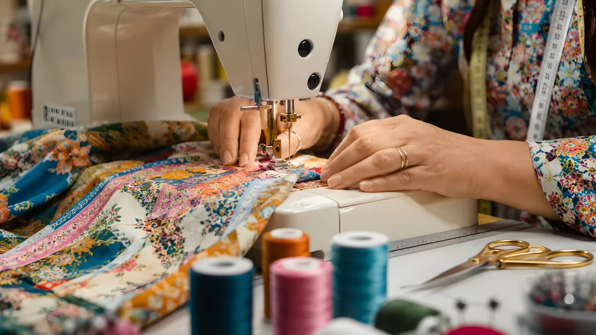 Näherin arbeitet an buntem Blumenstoff mit Nähmaschine
