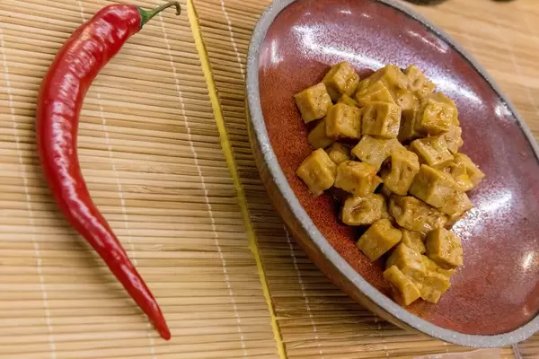 Nagel - vegane Bio-Tofu Würfel mit scharfem Chili auf einem Teller zum Probieren