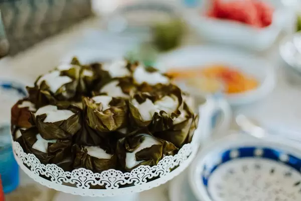 Nahaufnahme asiatische Reisküchlein umwickelt mit Bananenblättern im Fokus vor Frühstücksbuffet
