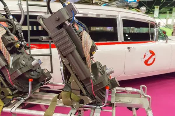 Nahaufnahme des Ghostbusters Proton Pack und Auto Ecto-1 im Hintergrund