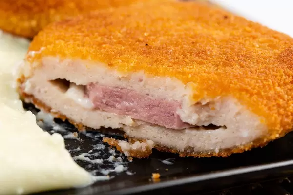 Nahaufnahme einer aufgeschnittenen Putenmedaillons, paniert und mit Schinken-Käse-Füllung