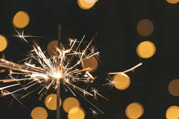 Nahaufnahme einer brennenden Wunderkerze vor Bokeh-Hintergrund