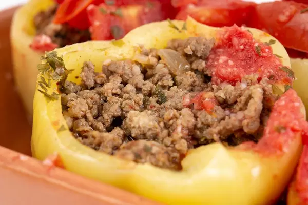 Nahaufnahme einer gelben gefüllten Paprika mit Hackfleisch, Kräutern und Tomaten