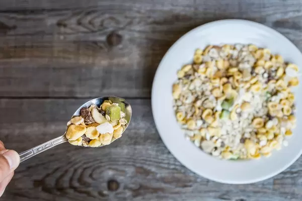 Nahaufnahme einer Hand mit Löffel und Müsli