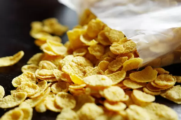 Nahaufnahme einer offenen Packung Cornflakes mit teilweise herausgefallenem Inhalt