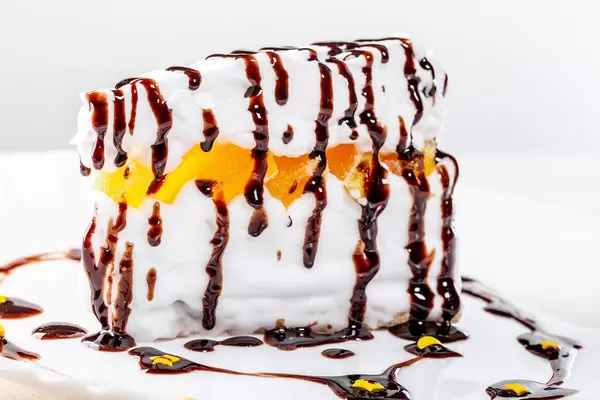 Nahaufnahme einer Stück Kuchen mit Orangenscheiben, Sahne und zerlaufener Schokoladensauce