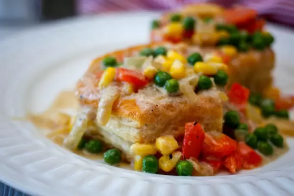Nahaufnahme einer vegetarischen Blätterteigpastete mit Erbsen, Mais und Paprika