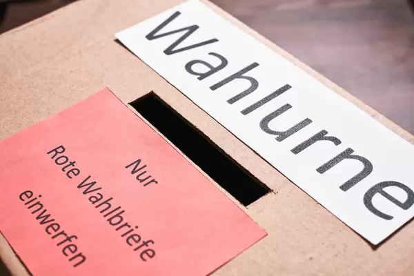 Nahaufnahme einer Wahlurne mit Schild "Nur rote Wahlbriefe einwerfen"