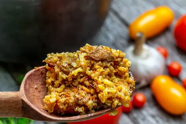 Nahaufnahme eines Holzlöffels mit Pilawreis und Fleisch