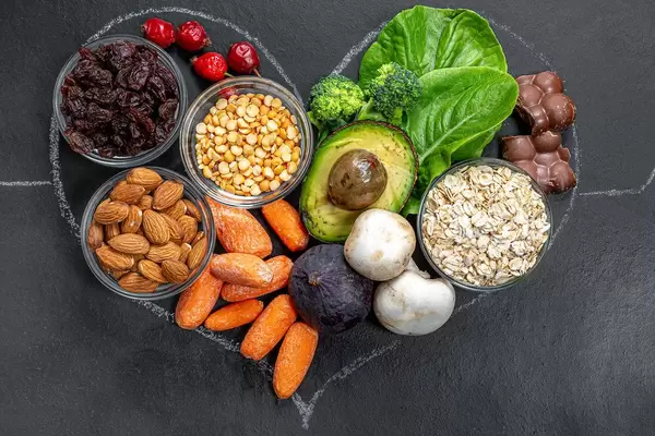 Nahaufnahme eines Kreideherz auf schwarzem Hintergrund gefüllt mit gesunden Produkten