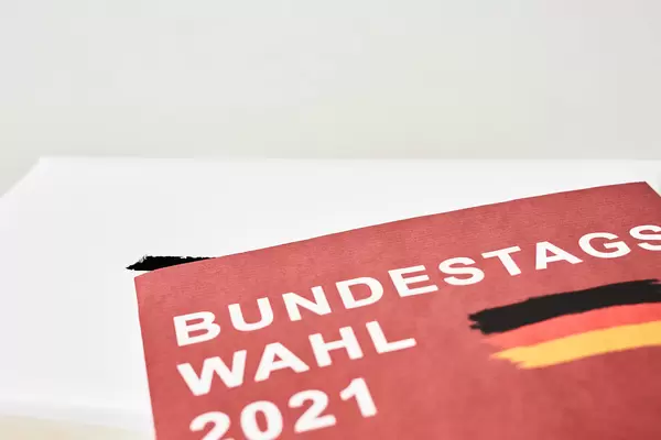 Nahaufnahme eines rotes Zettels mit der Schrift "Bundestagswahl 2021" und der deutschen Flagge