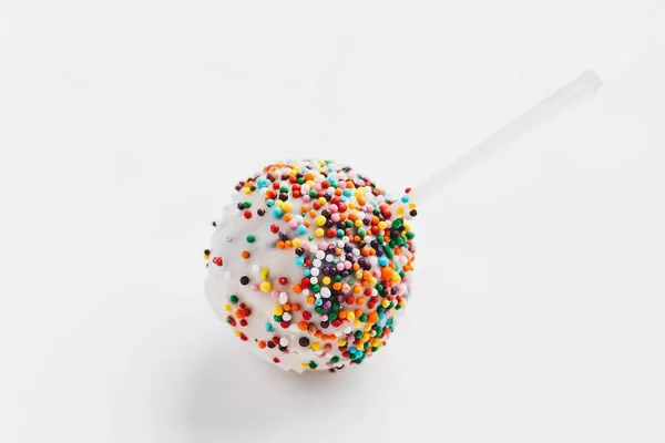 Nahaufnahme eins Lutschers mit bunter Streusel vor weißem Hintergrund