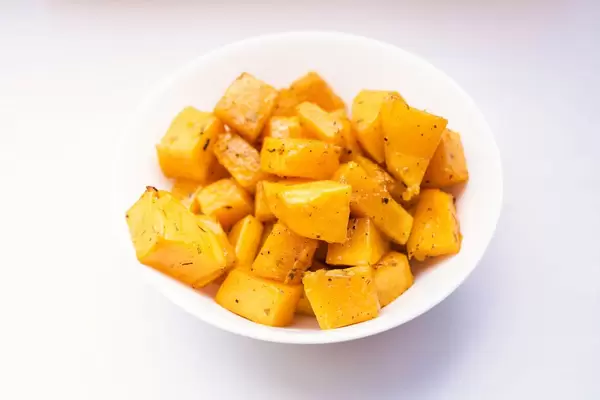 Nahaufnahme - Gebackene Kürbiswürfel in einer weißen Schale auf weißem Hintergrund