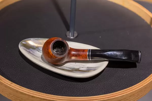 Nahaufnahme gefüllte und gerauchte Backpfeife liegt auf Schale auf rundem Tisch