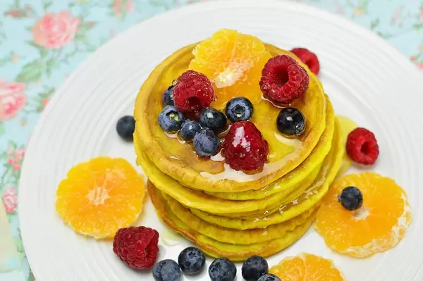 Nahaufnahme gestapelte Pfannkuchen mit Ahornsirup, Beeren und Orangenscheiben