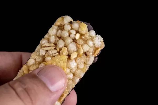 Nahaufnahme Hand mit Müsliriegel aus wertvollem Getreide, Banane und schwarzer Schokolade