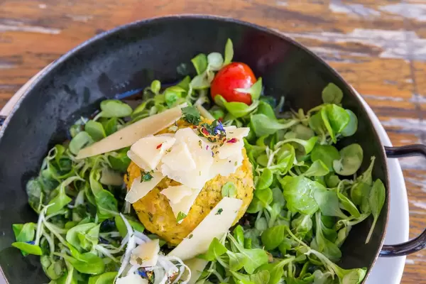 Nahaufnahme: Kürbisknödel in der Pfanne mit Feldsalat und Parmesan bei der Dauerstoa Alm