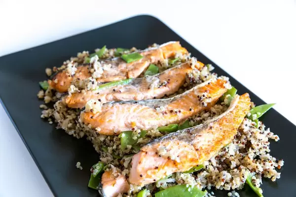 Nahaufnahme Lachssteifen vom Grill mit Blumenkohl-Quinova und Parmesanchips