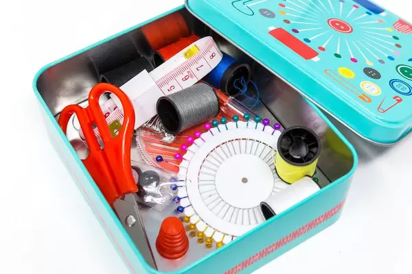 Nahaufnahme Nähutensilien wie Nadeln, Faden, Schere, Maßband und Fingerhut in Nähbox
