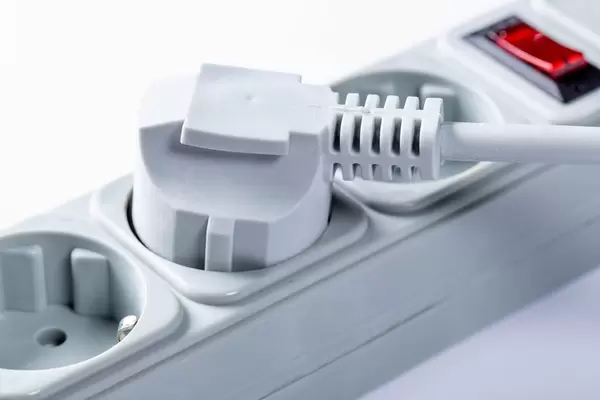 Nahaufnahme Stecker in Mehrfachbuchse mit Schalter vor weißem Hintergrund