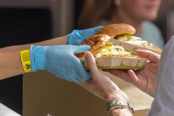 Nahaufnahme Verkäufer übergibt zwei Pappteller mit Hamburger an Kunden