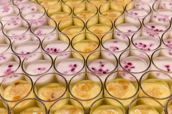 Nahaufnahme vom Nachtisch Granatapfel-Orangen Lassi und Safran Joghurt mit Trauben, Kardamom, Blaubeeren, Honig und Mandelblättchen, OMWest19