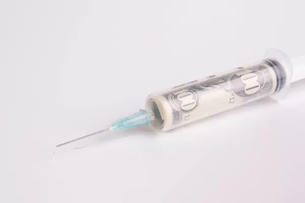 Nahaufnahme von amerikanischen Geldscheinen in einer Spritze, zum Thema Gesundheitswesen